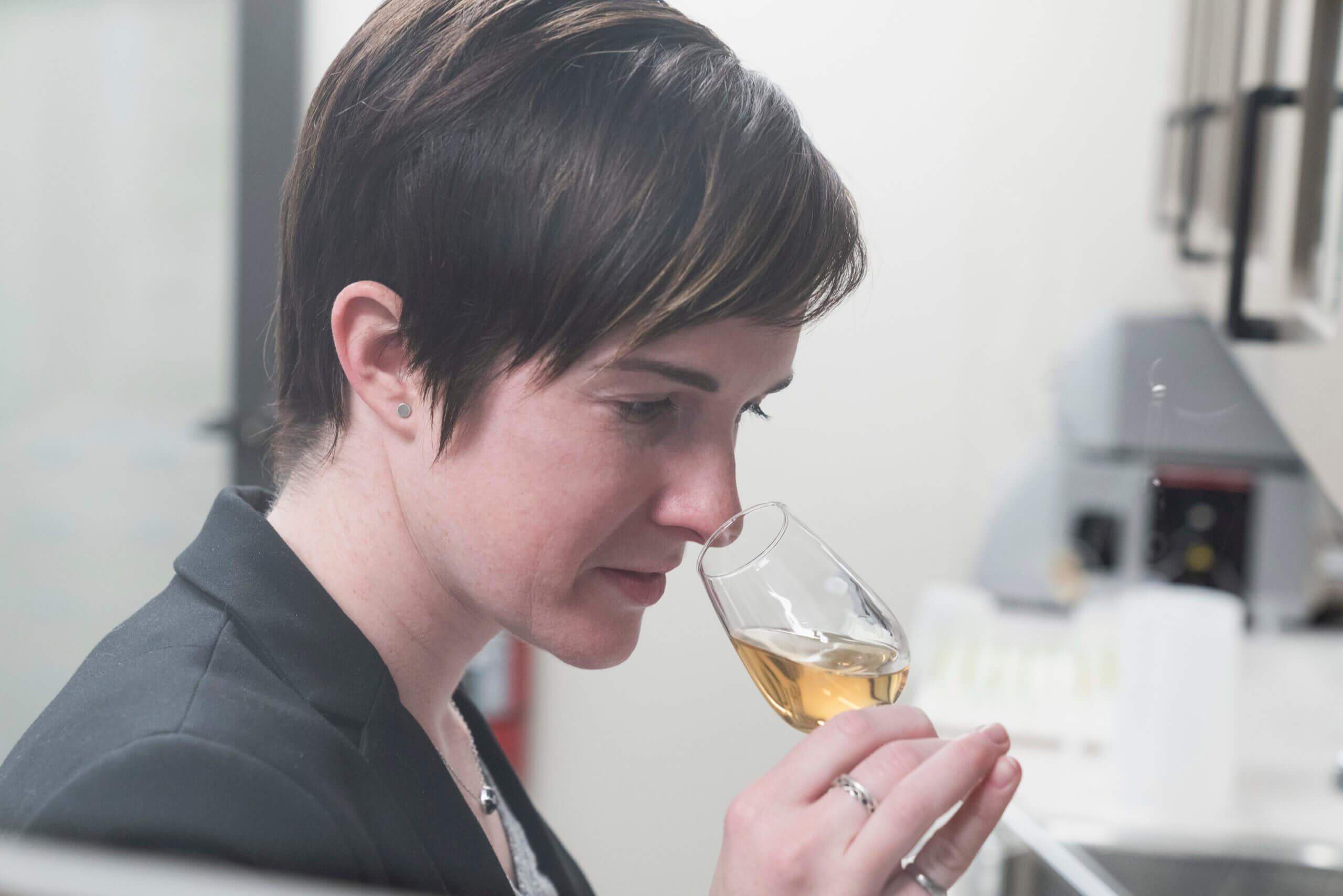 Alex Castle smelling a glass of whiskey in her lab