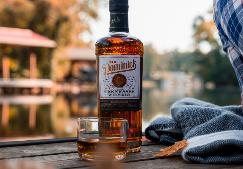 Straight Tennessee Whiskey bottle on a wooden table with a glass